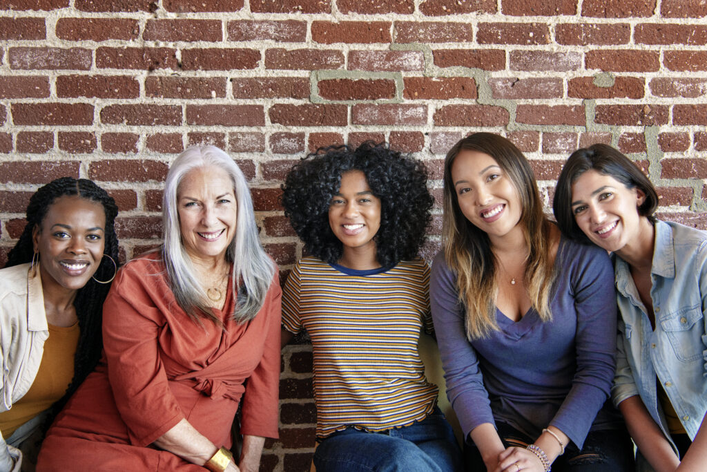 Diverse women sitting together by a brick wall